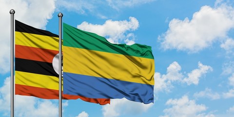 Uganda and Gabon flag waving in the wind against white cloudy blue sky together. Diplomacy concept, international relations.