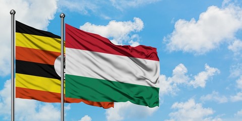 Uganda and Hungary flag waving in the wind against white cloudy blue sky together. Diplomacy concept, international relations.