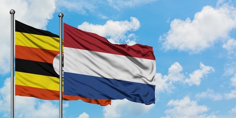 Uganda and Netherlands flag waving in the wind against white cloudy blue sky together. Diplomacy concept, international relations.