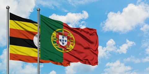 Uganda and Portugal flag waving in the wind against white cloudy blue sky together. Diplomacy concept, international relations.