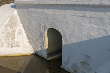 Painted white concrete drainage ditch design with hole in the form of an arch with the floor slab...