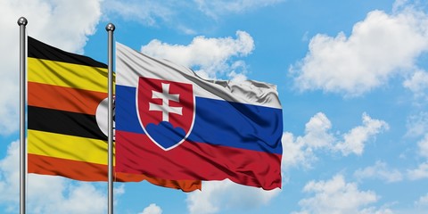 Uganda and Slovakia flag waving in the wind against white cloudy blue sky together. Diplomacy concept, international relations.