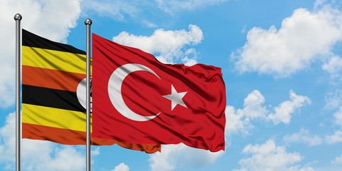 Uganda and Turkey flag waving in the wind against white cloudy blue sky together. Diplomacy concept, international relations.