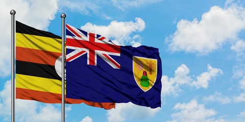 Uganda and Turks And Caicos Islands flag waving in the wind against white cloudy blue sky together. Diplomacy concept, international relations.