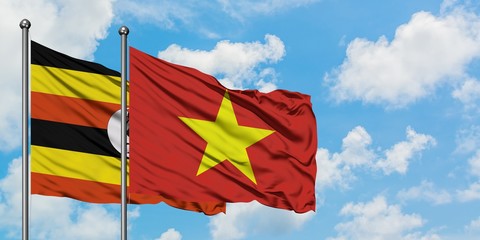 Uganda and Vietnam flag waving in the wind against white cloudy blue sky together. Diplomacy concept, international relations.