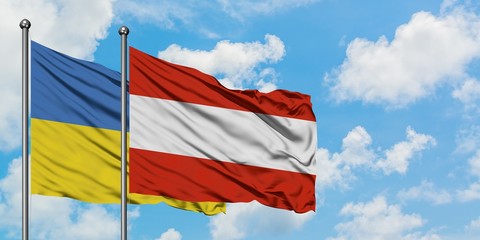 Ukraine and Austria flag waving in the wind against white cloudy blue sky together. Diplomacy concept, international relations.
