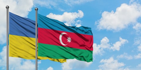 Ukraine and Azerbaijan flag waving in the wind against white cloudy blue sky together. Diplomacy concept, international relations.