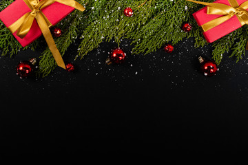 Christmas composition. Girlanda with red Christmas ornaments, gifts and snow on black background. Christmas, winter, new year concept. Flat lay, top view, copy space. © Julio Ricco