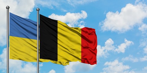 Ukraine and Belgium flag waving in the wind against white cloudy blue sky together. Diplomacy concept, international relations.