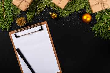 Christmas composition. Girlanda with Christmas ornaments and gifts on black background and blank notepad. Christmas, winter, new year concept. Flat lay, top view, copy space. © Julio Ricco
