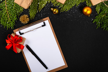 Christmas composition. Girlanda with Christmas ornaments and gifts on black background and blank notepad. Christmas, winter, new year concept. Flat lay, top view, copy space. © Julio Ricco