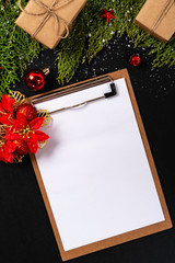 Christmas composition. Girlanda with Christmas ornaments and gifts on black background and blank notepad. Christmas, winter, new year concept. Flat lay, top view, copy space. © Julio Ricco