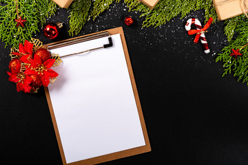 Christmas composition. Girlanda with Christmas ornaments and gifts on black background and blank notepad. Christmas, winter, new year concept. Flat lay, top view, copy space. © Julio Ricco