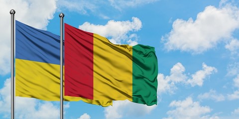 Ukraine and Guinea flag waving in the wind against white cloudy blue sky together. Diplomacy concept, international relations.