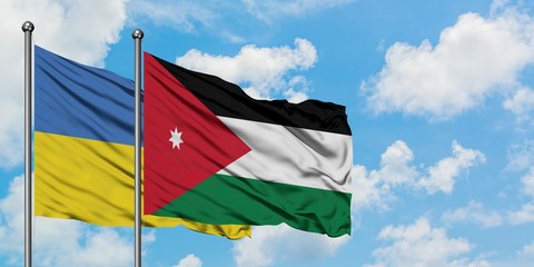 Ukraine and Jordan flag waving in the wind against white cloudy blue sky together. Diplomacy concept, international relations.
