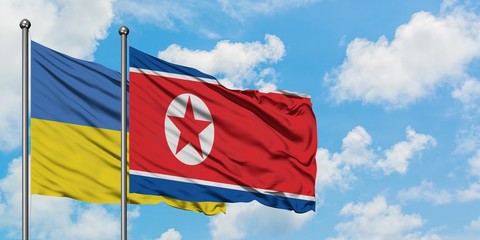 Ukraine and North Korea flag waving in the wind against white cloudy blue sky together. Diplomacy concept, international relations.