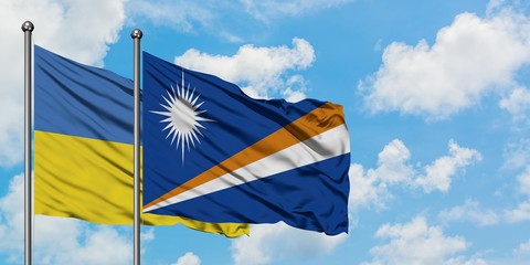 Ukraine and Marshall Islands flag waving in the wind against white cloudy blue sky together. Diplomacy concept, international relations.