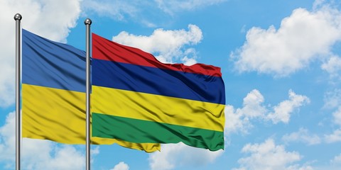 Ukraine and Mauritius flag waving in the wind against white cloudy blue sky together. Diplomacy concept, international relations.