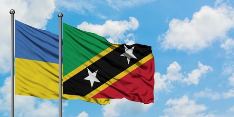 Ukraine and Saint Kitts And Nevis flag waving in the wind against white cloudy blue sky together. Diplomacy concept, international relations.