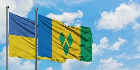 Ukraine and Saint Vincent And The Grenadines flag waving in the wind against white cloudy blue sky...