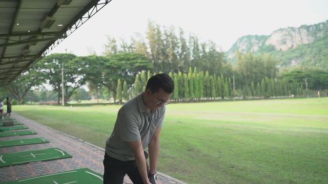 Close up male pro golf swing at a driving range
