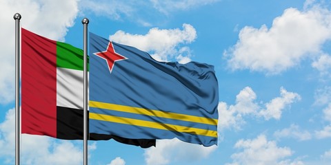 United Arab Emirates and Aruba flag waving in the wind against white cloudy blue sky together. Diplomacy concept, international relations.