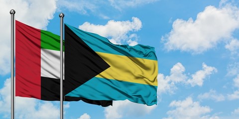 United Arab Emirates and Bahamas flag waving in the wind against white cloudy blue sky together. Diplomacy concept, international relations.