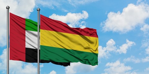 United Arab Emirates and Bolivia flag waving in the wind against white cloudy blue sky together. Diplomacy concept, international relations.