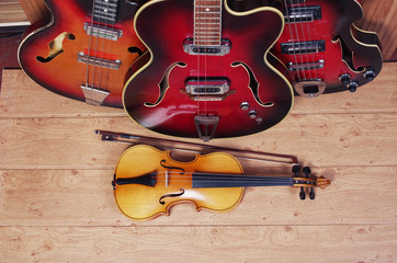 Electric guitar, violin, carnival mask on a wooden texture