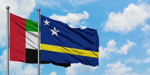 United Arab Emirates and Curacao flag waving in the wind against white cloudy blue sky together. Diplomacy concept, international relations.