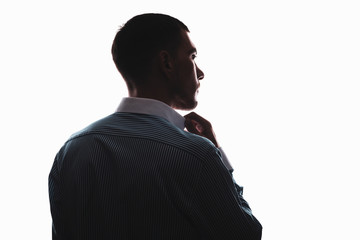 silhouette of a European man from the back in a business shirt adjusts the collar look to the side