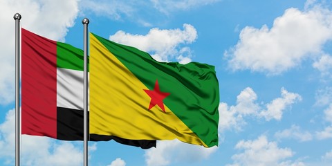 United Arab Emirates and French Guiana flag waving in the wind against white cloudy blue sky together. Diplomacy concept, international relations.