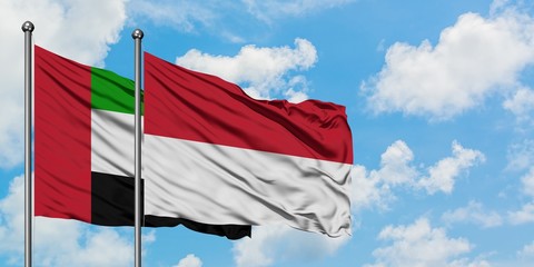 United Arab Emirates and Indonesia flag waving in the wind against white cloudy blue sky together. Diplomacy concept, international relations.