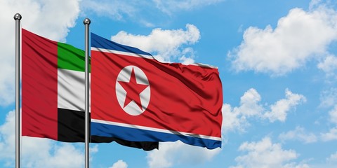 United Arab Emirates and North Korea flag waving in the wind against white cloudy blue sky together. Diplomacy concept, international relations.