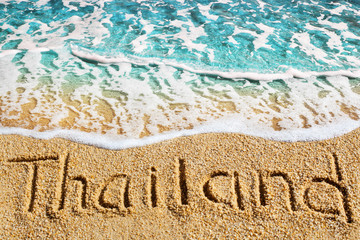 Word THAILAND written on yellow sand, blue sea wave background, handwritten letters inscription, turquoise ocean water, tropical island beach vacation concept, summer holidays banner, text copy space