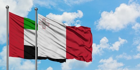 United Arab Emirates and Malta flag waving in the wind against white cloudy blue sky together. Diplomacy concept, international relations.