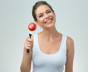 smiling sporty woman in white casual vest holding red tomato on fork.