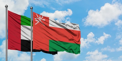 United Arab Emirates and Oman flag waving in the wind against white cloudy blue sky together. Diplomacy concept, international relations.