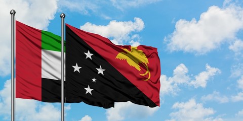 United Arab Emirates and Papua New Guinea flag waving in the wind against white cloudy blue sky together. Diplomacy concept, international relations.