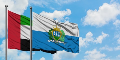 United Arab Emirates and San Marino flag waving in the wind against white cloudy blue sky together. Diplomacy concept, international relations.