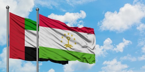 United Arab Emirates and Tajikistan flag waving in the wind against white cloudy blue sky together. Diplomacy concept, international relations.