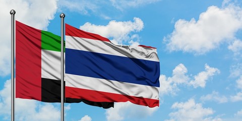 United Arab Emirates and Thailand flag waving in the wind against white cloudy blue sky together. Diplomacy concept, international relations.