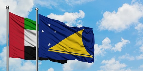 United Arab Emirates and Tokelau flag waving in the wind against white cloudy blue sky together. Diplomacy concept, international relations.