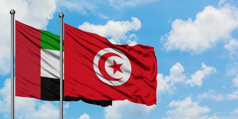 United Arab Emirates and Tunisia flag waving in the wind against white cloudy blue sky together. Diplomacy concept, international relations.