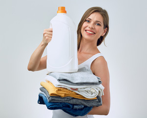 smiling woman holding clothes and laundry detergent .