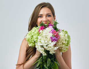 face portrait of smiling woman holding big flowers bouquet in front of face.