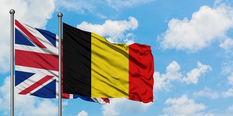 United Kingdom and Belgium flag waving in the wind against white cloudy blue sky together. Diplomacy concept, international relations.