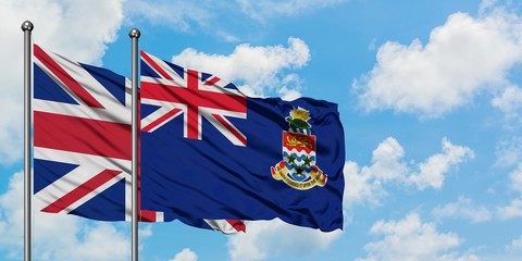 United Kingdom and Cayman Islands flag waving in the wind against white cloudy blue sky together. Diplomacy concept, international relations.