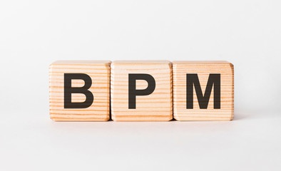 BPM letters of wooden blocks in pillar form on white background, copy space