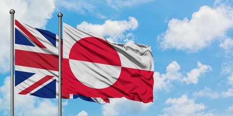 United Kingdom and Greenland flag waving in the wind against white cloudy blue sky together. Diplomacy concept, international relations.